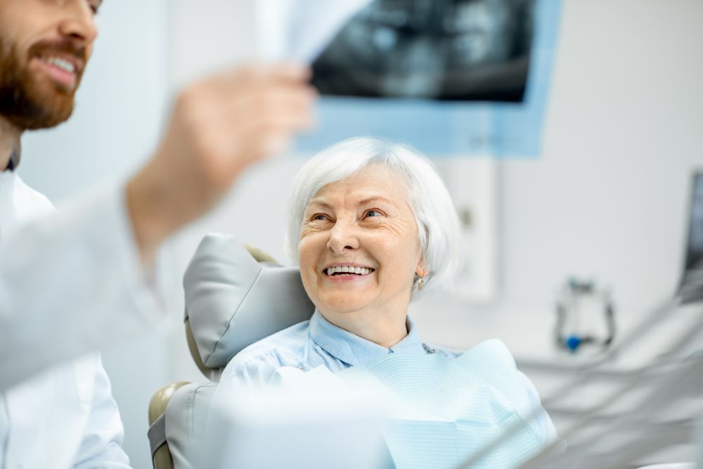 Elderly Woman Smiling At The Dentist While Viewing A Dental X-ray