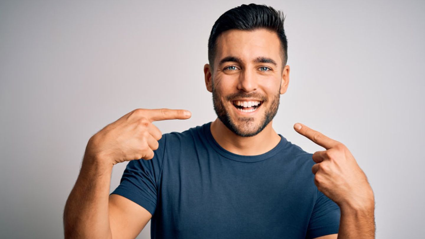 Man Pointing At His Teeth After Teeth Whitening Treatment